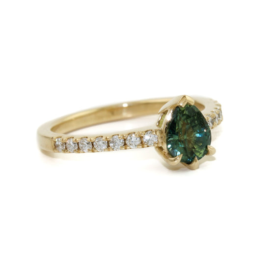 An alluring seafoam green sapphire, cut in the shape of a teardrop to flatter and elongate the finger. This beautiful stone is set in a 14k gold bezel, surrounded by brilliant tiny diamonds.