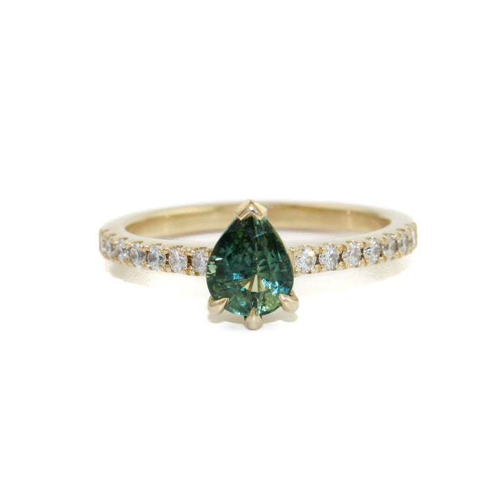 An alluring seafoam green sapphire, cut in the shape of a teardrop to flatter and elongate the finger. This beautiful stone is set in a 14k gold bezel, surrounded by brilliant tiny diamonds.