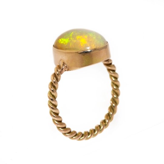 A dreamy 14kt gold ring made by Kingdom. This ring features a stunning oval-shaped Welo Opal, set into a gold band made in a twisted rope style, creating a timeless and elegant piece that would pair well with other rings or as a stand-alone piece. 