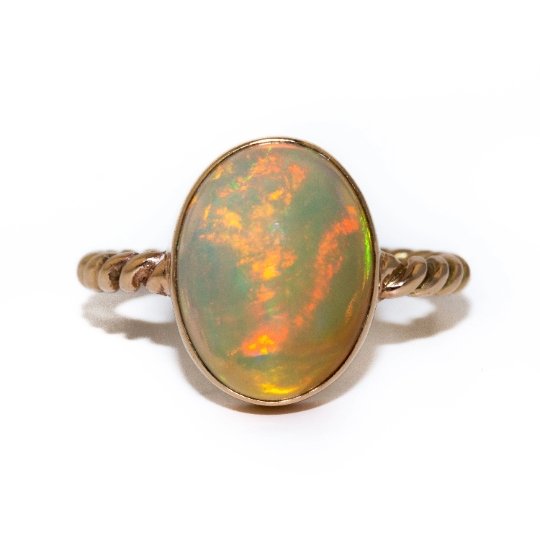 A dreamy 14kt gold ring made by Kingdom. This ring features a stunning oval-shaped Welo Opal, set into a gold band made in a twisted rope style, creating a timeless and elegant piece that would pair well with other rings or as a stand-alone piece. 